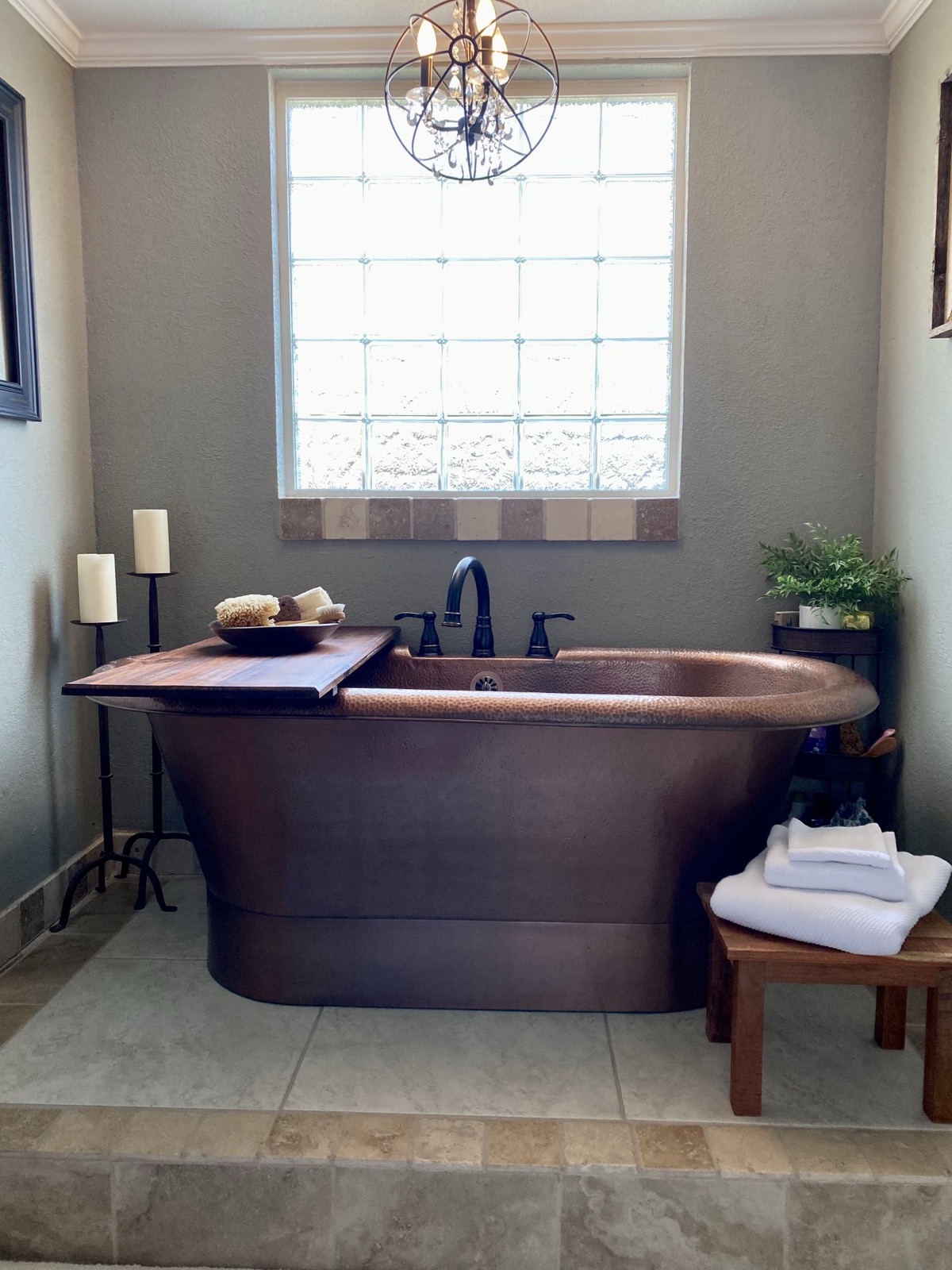 Hammered copper soaking tub with glass-block window and chandelier in addition master bath